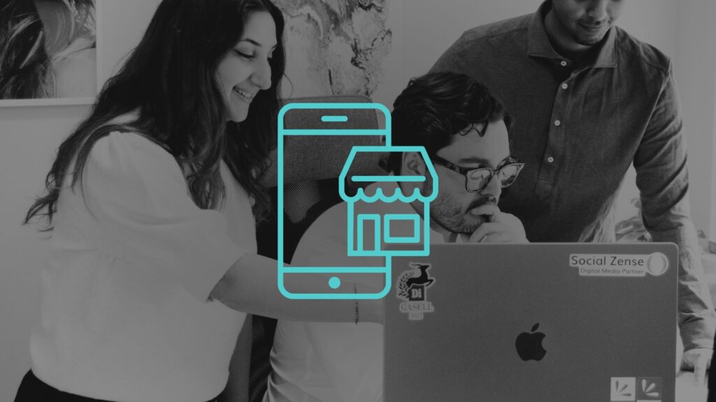 Tre personer tittar på en dator i ett kontorslandskap.