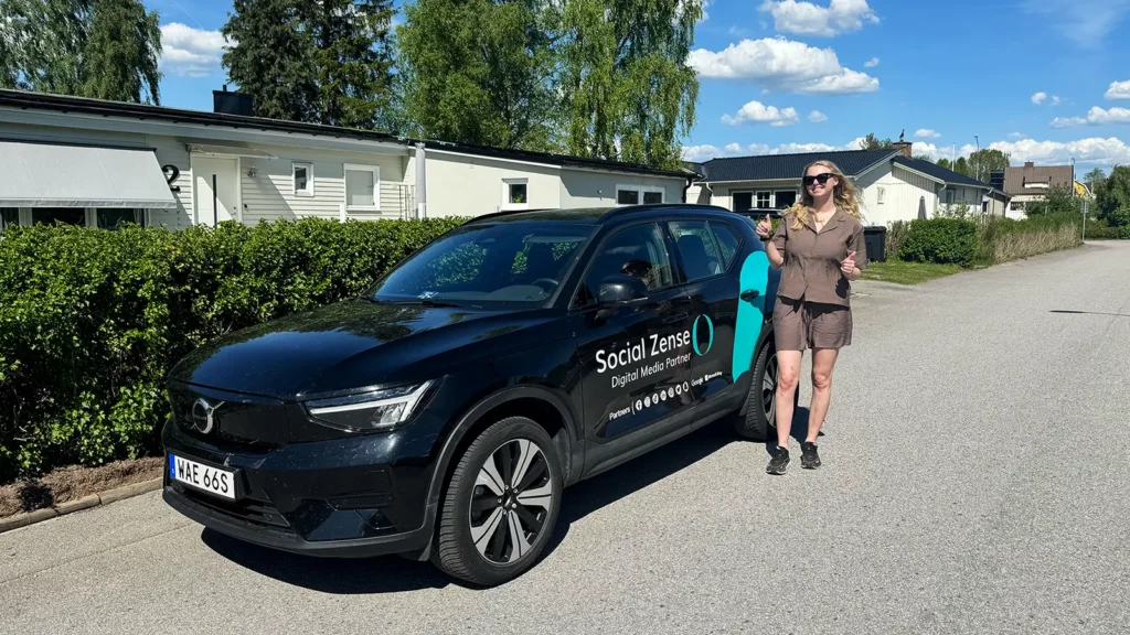Sanna Norén framför en bil med Social Zense logotyp.