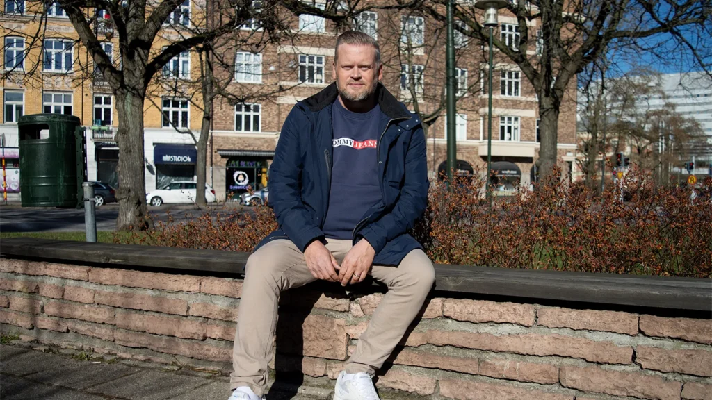 Stefan Björling sitter på en bänk i en solig park.